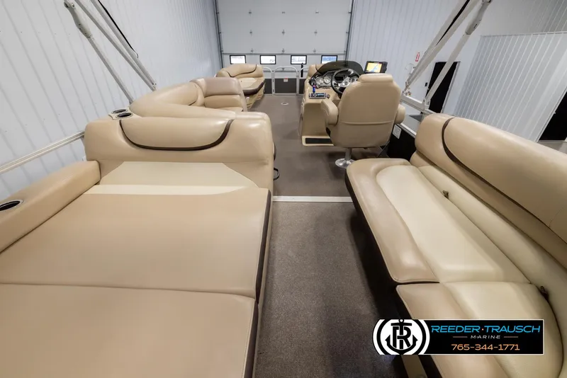 Slide: The Image of 2016 Sun Tracker 24 Party Barge interior with beige seating, steering console, and carpeted floor. - 18