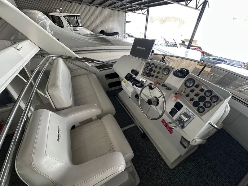 Slide: The Image of 2003 Carver 356 Motor Yacht helm with dual seats and control panel in a marina. - 28