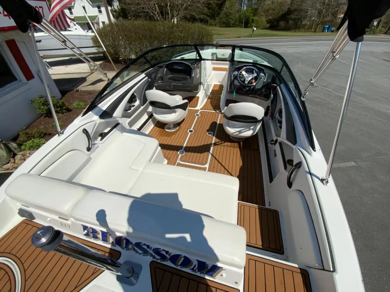Slide: The Image of 2017 Monterey 217 Outboard boat interior with seating and steering wheel, docked outdoors. - 10