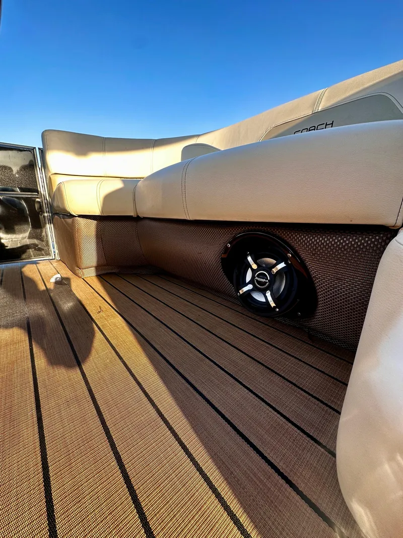 Slide: The Image of 2019 Coach Pontoons 230 RF interior with cushioned seating and speaker, under clear blue sky. - 13