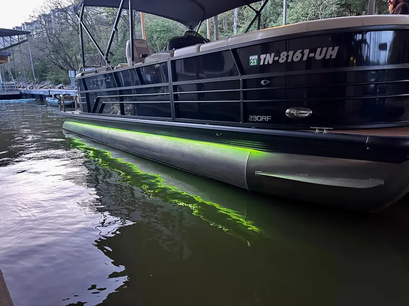 Slide: The Image of 2019 Coach Pontoons 230 RF with green underwater lights docked on a calm lake. - 23