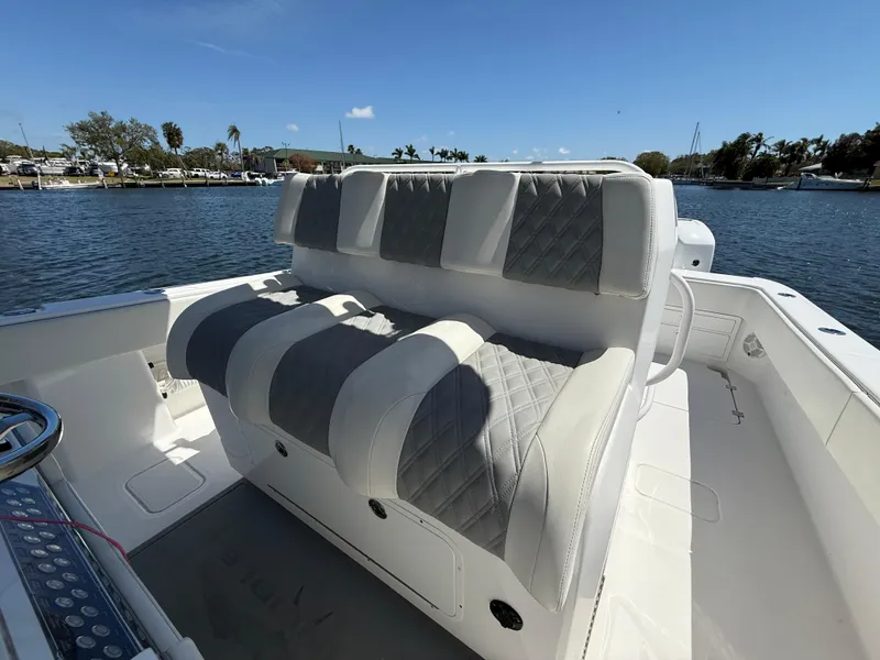 Slide: The Image of Luxury seating on 2022 Invincible 33 Catamaran, featuring quilted upholstery, docked by a scenic waterfront. - 13