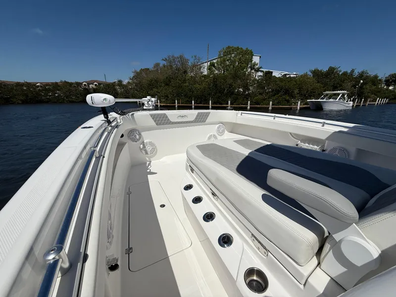 Slide: The Image of 2022 Invincible 33 Catamaran boat interior with cushioned seating, docked by a scenic waterway. - 15