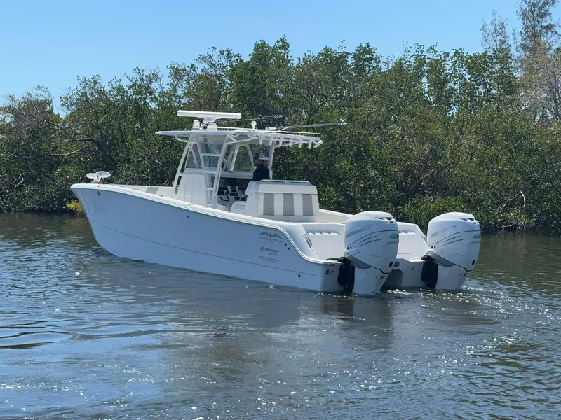 Slide: The Image of 2022 Invincible 33 Catamaran on water, featuring dual outboard motors, surrounded by trees. - 5