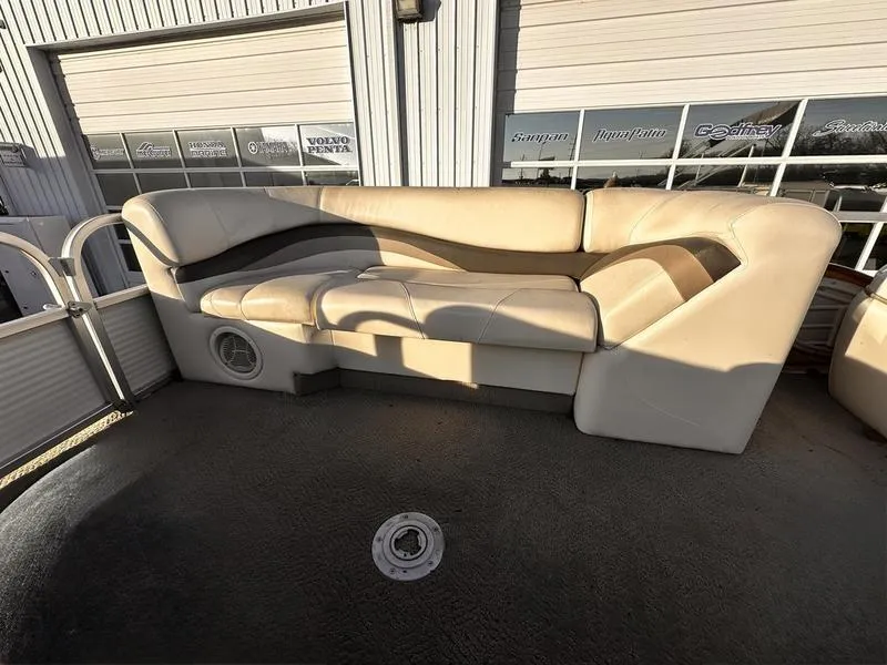 Slide: The Image of 2006 Sun Tracker PARTY BARGE seating with beige upholstery, set against a marina backdrop. - 18