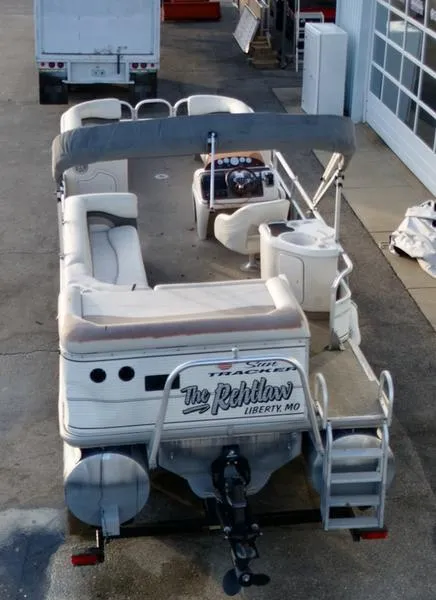 Slide: The Image of 2006 Sun Tracker PARTY BARGE pontoon boat with seating and canopy, parked near a garage. - 4