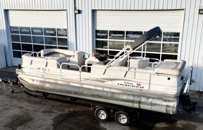 Slide: The Image of 2006 Sun Tracker PARTY BARGE pontoon boat on trailer, parked outside a garage. - 5