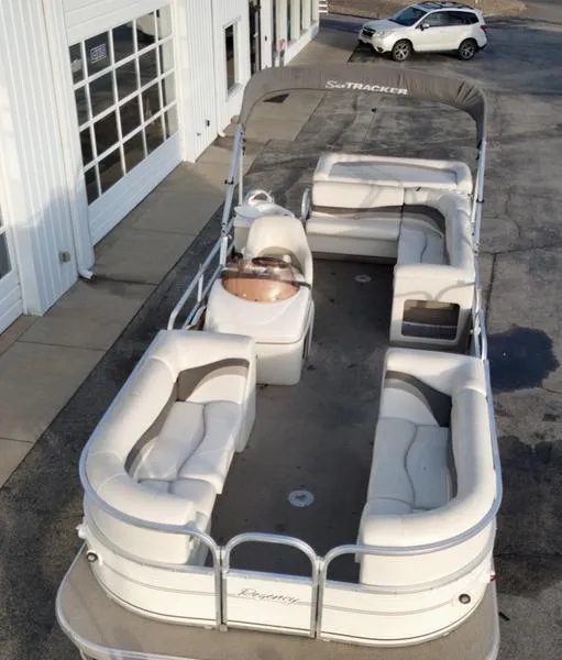 Slide: The Image of 2006 Sun Tracker PARTY BARGE pontoon boat with spacious seating and canopy, parked near a building. - 6