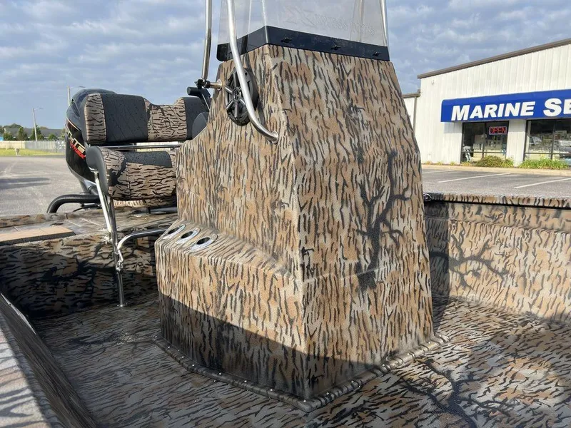 Slide: The Image of 2025 Xpress H210 BAY boat with camouflage design near a marine service building. - 1