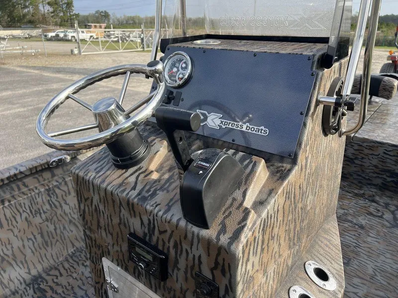 Slide: The Image of 2025 Xpress H210 BAY boat console with steering wheel and controls, featuring camo design. - 15