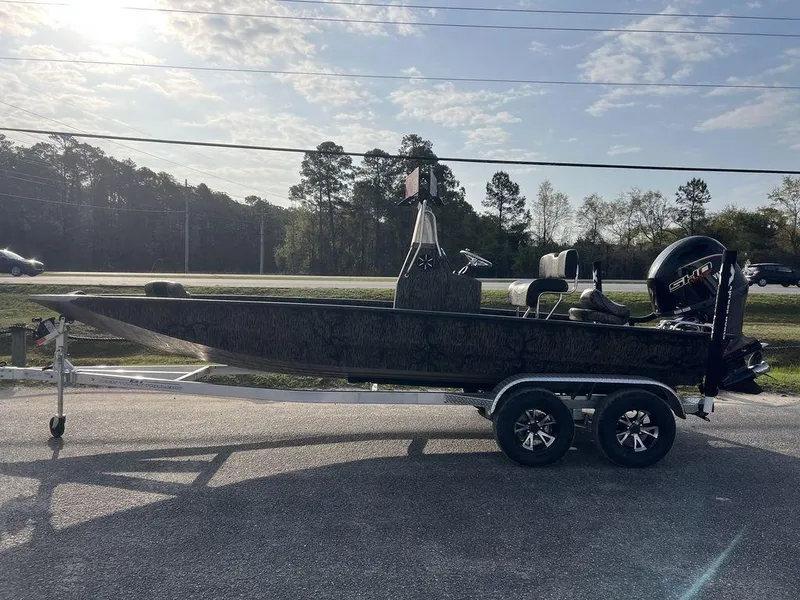 Slide: The Image of 2025 Xpress H210 BAY boat on trailer, parked outdoors under a partly cloudy sky. - 9
