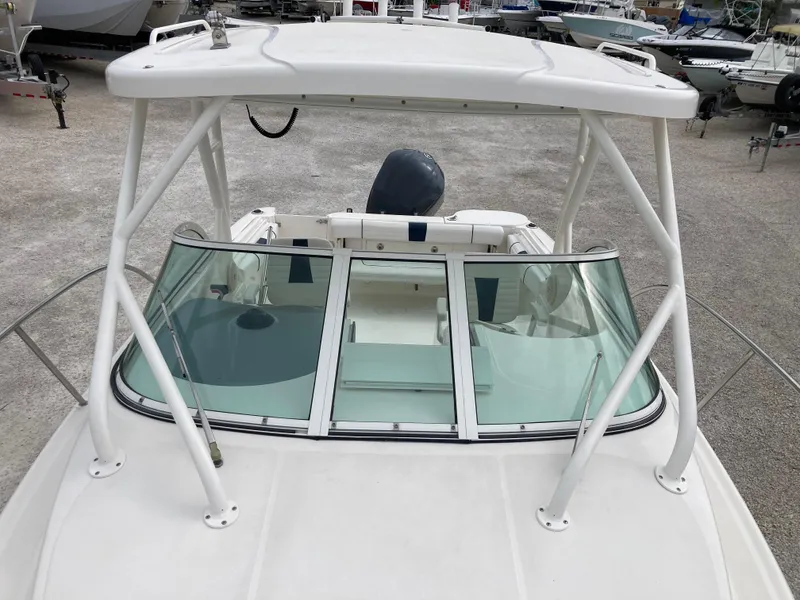 Slide: The Image of 2014 Wellcraft 232 Coastal boat with white frame and windshield, docked on gravel. - 15