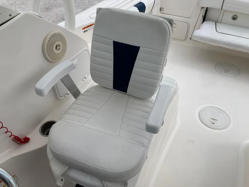 Slide: The Image of Captain's chair on 2014 Wellcraft 232 Coastal boat, featuring white and navy upholstery. - 17