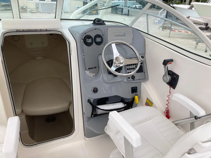 Slide: The Image of 2014 Wellcraft 232 Coastal boat cockpit with steering wheel and cabin entrance. - 8