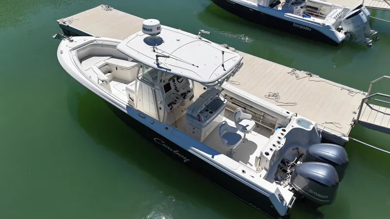 Slide: The Image of 2015 Sailfish 290cc boat docked, featuring dual engines and spacious deck layout. - 2