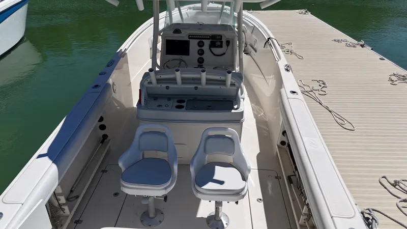 Slide: The Image of 2015 Sailfish 290cc boat interior with dual seats and control panel, docked by the water. - 8