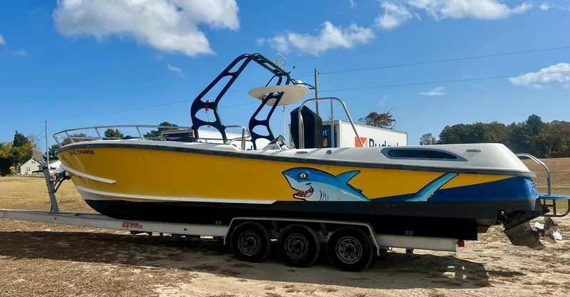 Slide: The Image of Yellow Centurion Parasail Boat 2010 with shark graphic on trailer, under blue sky. - 6