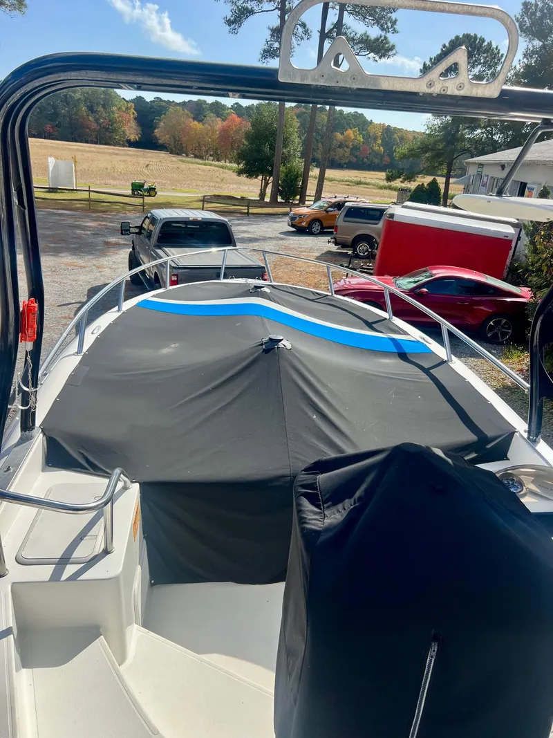 Slide: The Image of 2010 Centurion Parasail Boat covered, parked outdoors with vehicles and trees in the background. - 7