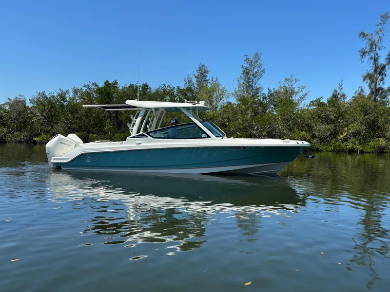 Slide: The Image of 2023 Boston Whaler 280 Vantage boat on calm water, surrounded by trees. - 0