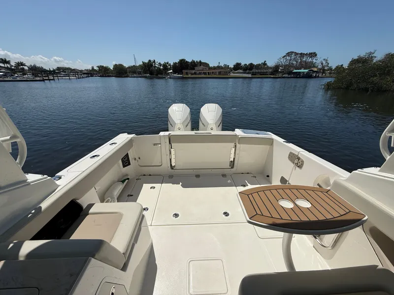 Slide: The Image of 2023 Boston Whaler 280 Vantage boat interior with seating and table, overlooking calm waters. - 10