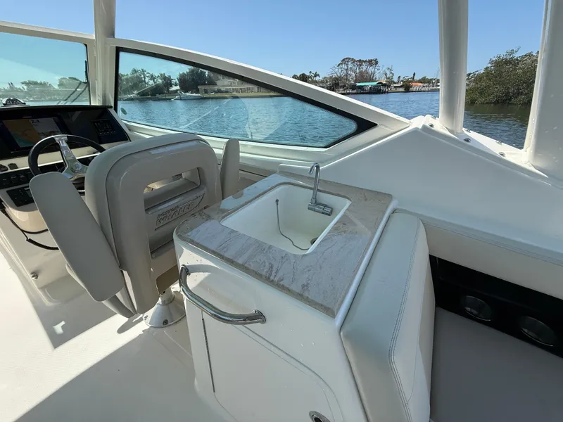 Slide: The Image of 2023 Boston Whaler 280 Vantage boat interior with helm, sink, and scenic water view. - 16