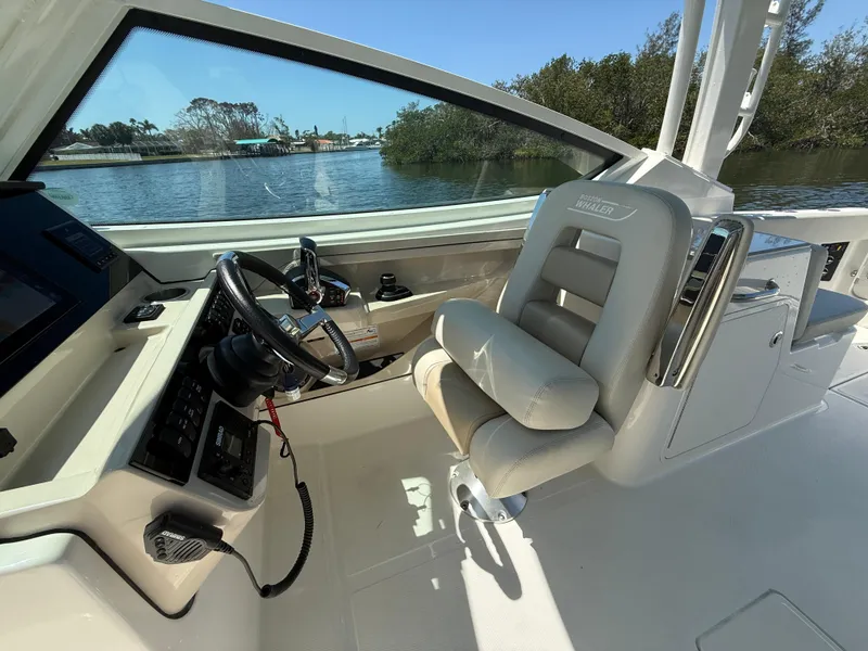 Slide: The Image of 2023 Boston Whaler 280 Vantage helm with steering wheel and comfortable seating by the water. - 18