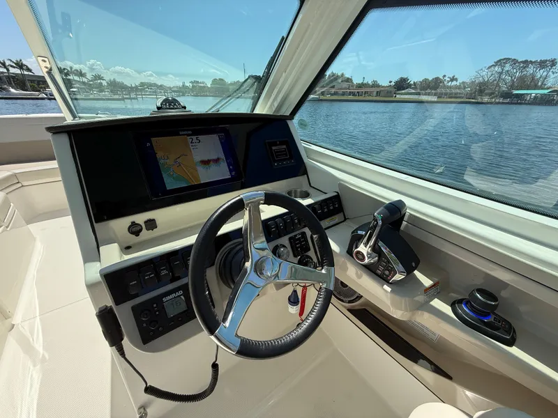Slide: The Image of 2023 Boston Whaler 280 Vantage helm with steering wheel and navigation display, overlooking water. - 19