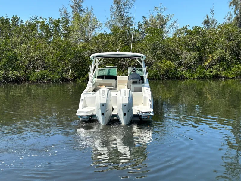 Slide: The Image of 2023 Boston Whaler 280 Vantage boat on calm water, surrounded by lush greenery. - 3