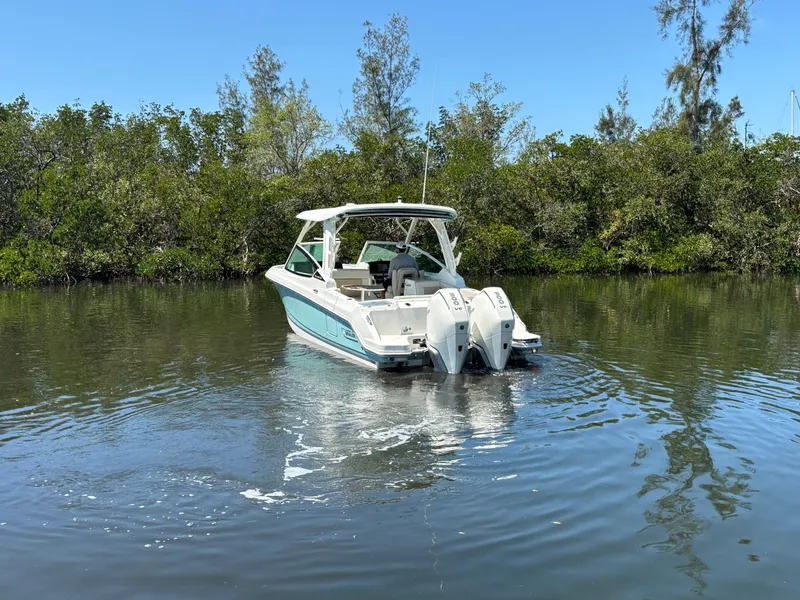 Slide: The Image of 2023 Boston Whaler 280 Vantage boat on calm water near lush greenery. - 4