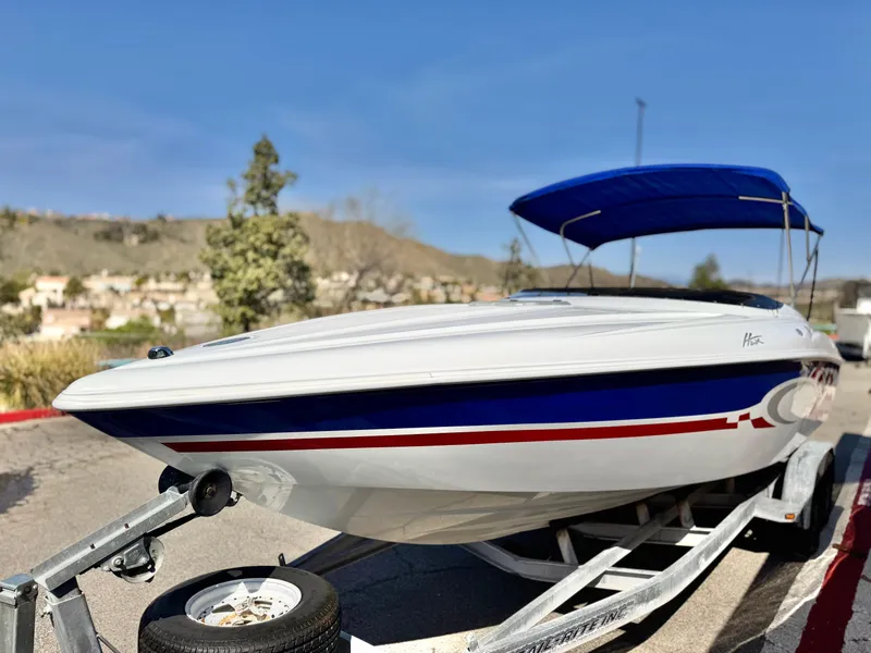 Slide: The Image of 2002 Baja 24H2X boat on trailer with blue canopy, parked outdoors. - 3