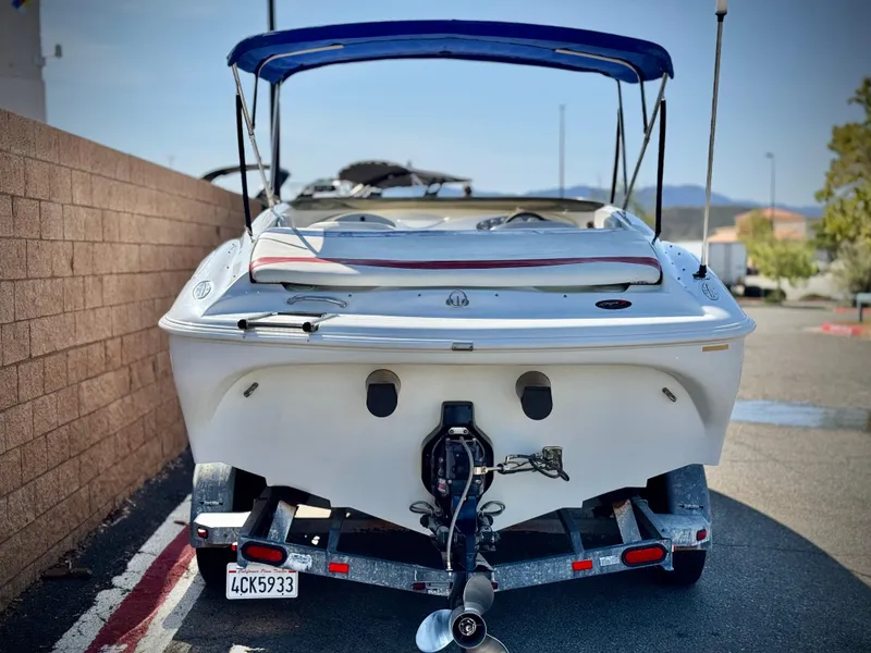 Slide: The Image of 2002 Baja 24H2X boat with blue canopy on trailer, parked outdoors. - 4