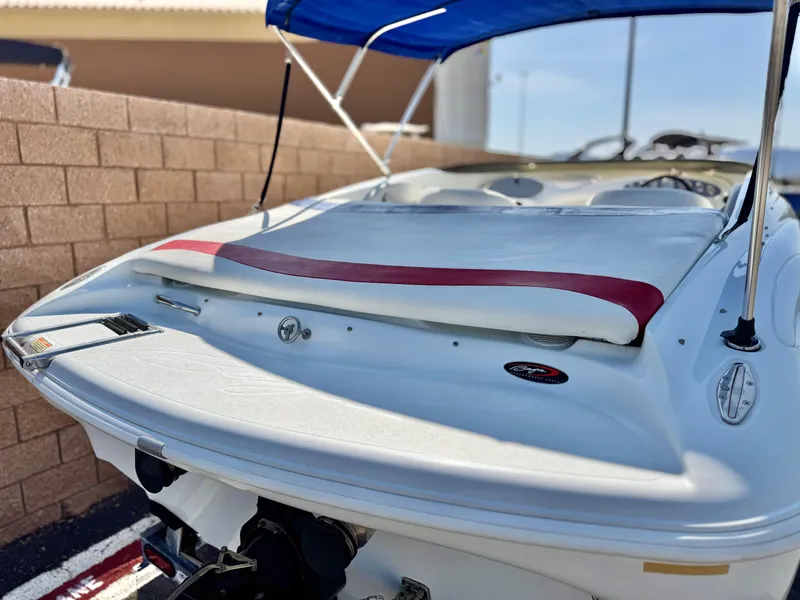 Slide: The Image of 2002 Baja 24H2X boat with blue canopy, red accents, and sleek design, parked near a brick wall. - 6