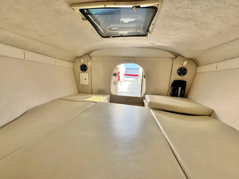 Slide: The Image of Interior cabin of a 2002 Baja 24H2X boat, featuring cushioned seating and a skylight. - 19