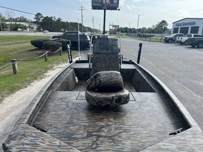Slide: The Image of 2025 Xpress XP18CC boat with camouflage design, parked outdoors near a showroom. - 7