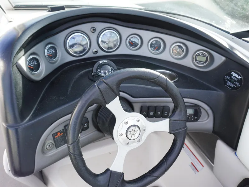 Slide: The Image of Steering wheel and dashboard of a 2013 Bryant 220 boat with gauges and controls. - 13