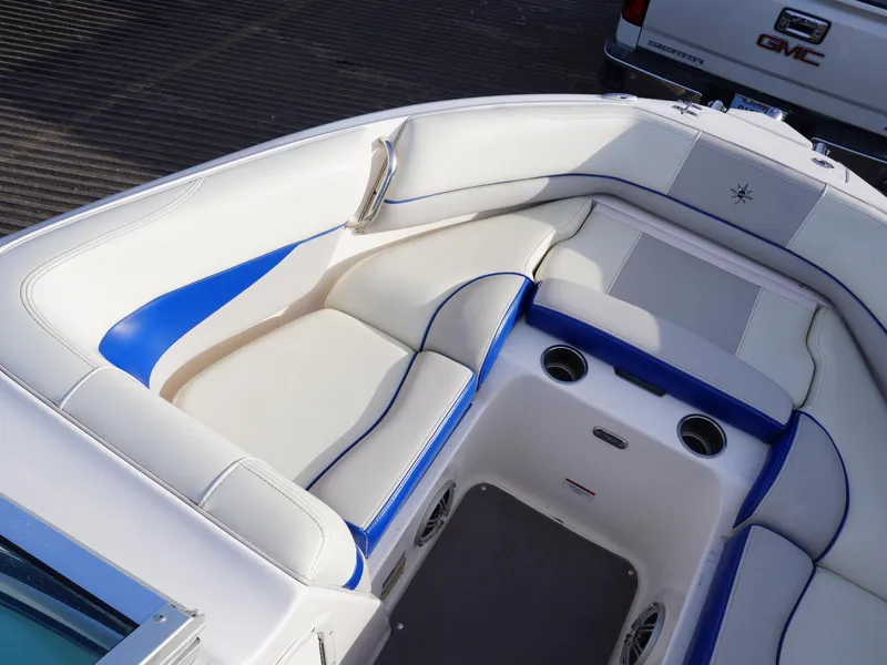 Slide: The Image of 2013 Bryant 220 boat interior with white and blue seating, cup holders, and sleek design. - 19