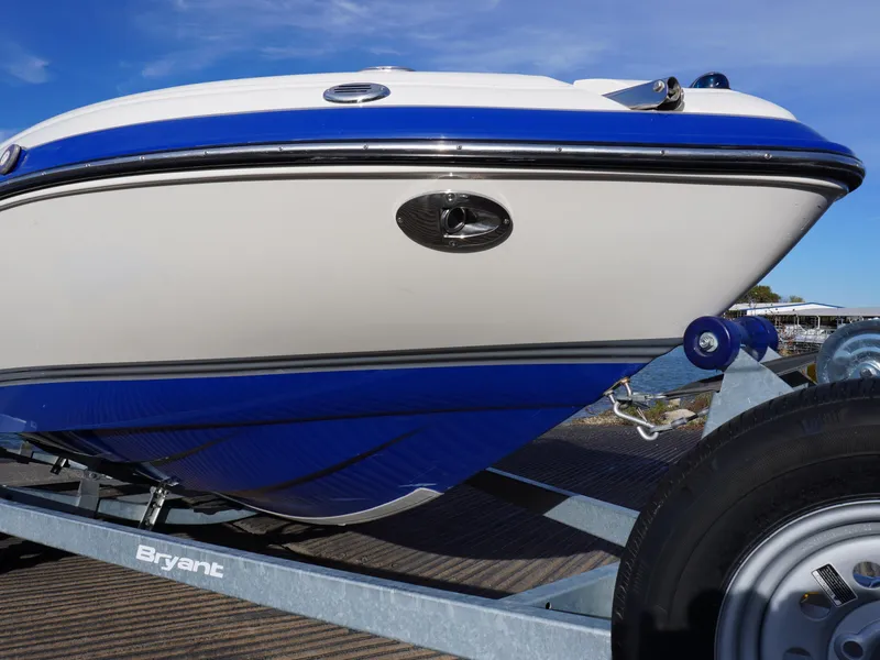 Slide: The Image of 2013 Bryant 220 boat on trailer, blue and white hull, sunny day. - 2