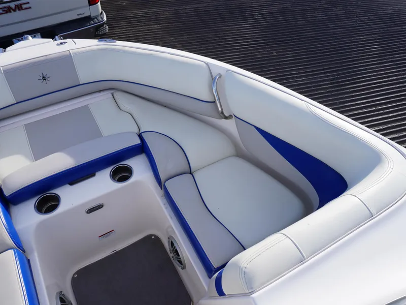 Slide: The Image of 2013 Bryant 220 boat interior with white and blue seating, cup holders, and sleek design. - 20