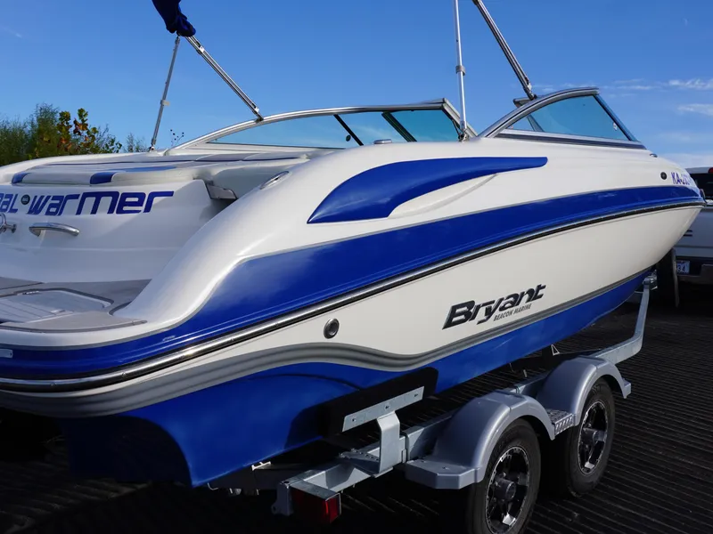 Slide: The Image of 2013 Bryant 220 boat on trailer, blue and white design, clear sky background. - 7