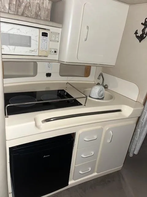 Slide: The Image of Compact kitchen in a 1996 Sea Ray 290 Sundancer boat with microwave, sink, and mini-fridge. - 13