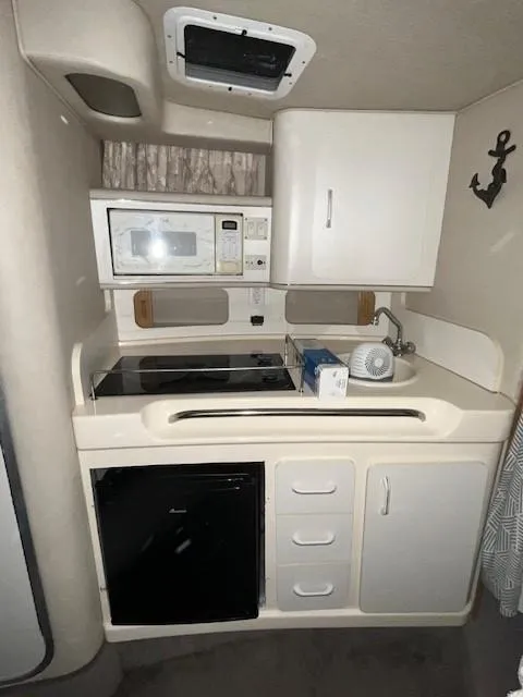 Slide: The Image of 1996 Sea Ray 290 Sundancer boat kitchenette with microwave, stove, and fridge. - 19