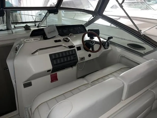 Slide: The Image of 1996 Sea Ray 290 Sundancer boat cockpit with white seating and steering wheel. - 9