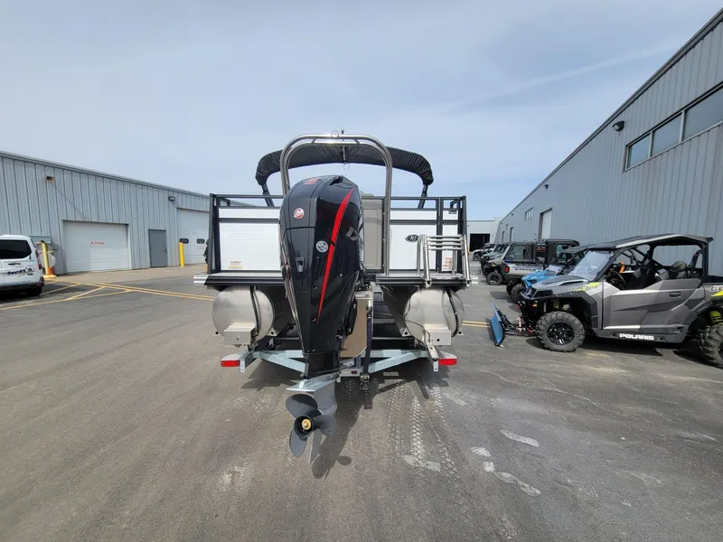 Slide: The Image of 2023 Angler Qwest 2285 Fish N Cruise boat with outboard motor, parked near industrial buildings. - 4