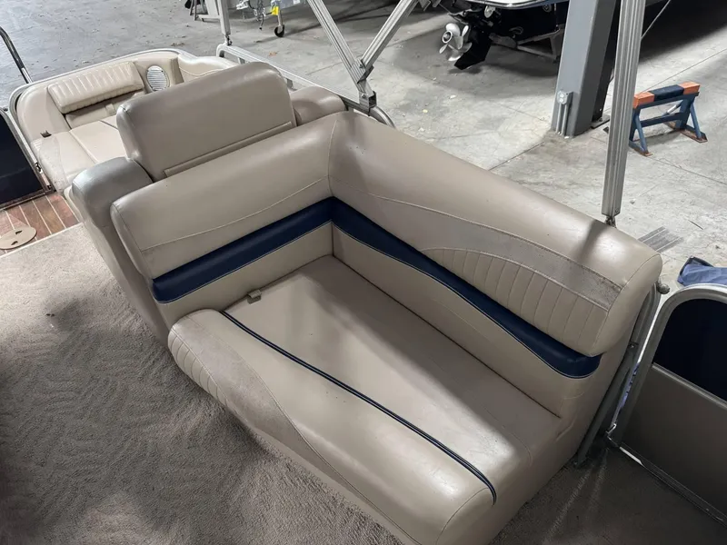 Slide: The Image of Interior seating of a 2012 Berkshire 223SLX STS boat, featuring beige and blue upholstery. - 6