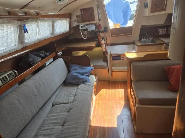 Slide: The Image of Interior of a 1984 Newport 33 sailboat with cozy seating and wooden flooring. - 3