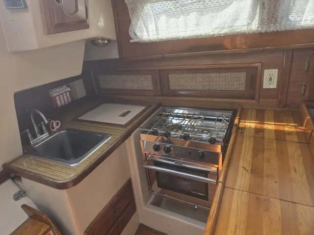Slide: The Image of Compact kitchen in a 1984 Newport 33 sailboat with stove, sink, and wooden countertops. - 4