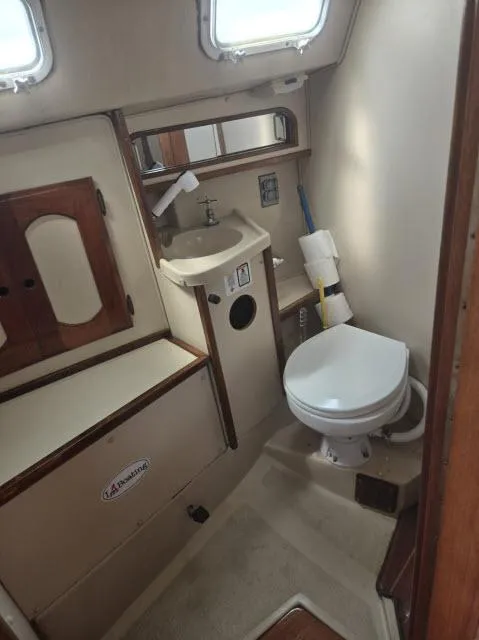 Slide: The Image of 1984 Newport 33 boat bathroom with sink, toilet, and storage cabinets. - 7