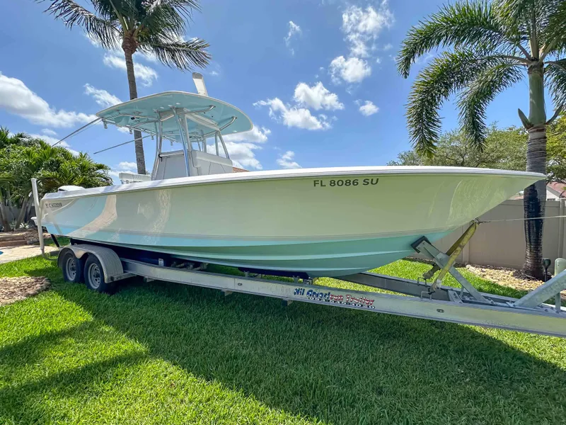 Slide: The Image of 2021 Contender 30 Tournament boat on trailer, parked on grass with palm trees. - 2