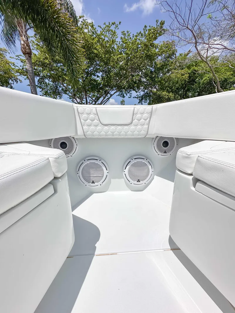 Slide: The Image of 2021 Contender 30 Tournament boat interior with white seating and speakers, surrounded by trees. - 20