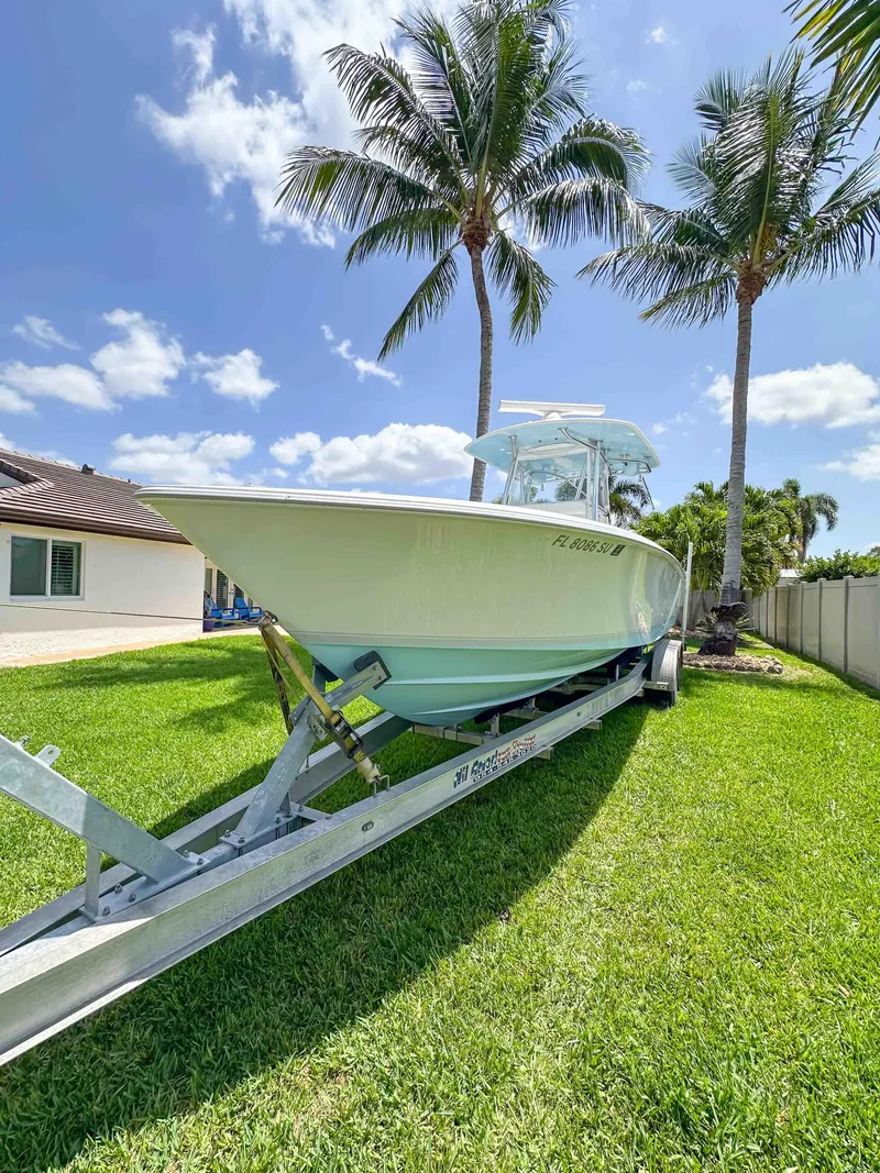 Slide: The Image of 2021 Contender 30 Tournament boat on trailer, parked on grass with palm trees in the background. - 4